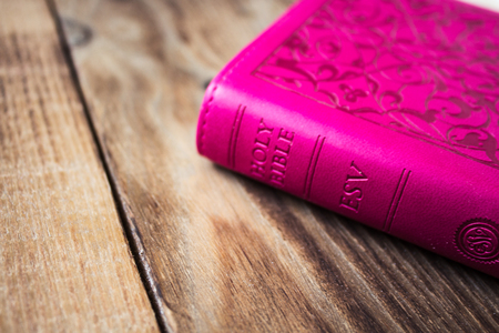a pink closed bible on wooden backgroundの写真素材