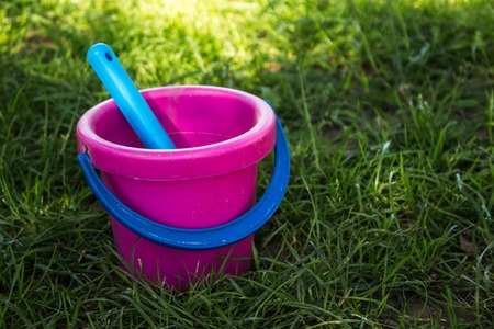 pink baby bucket and blue shovel on the lawnの写真素材