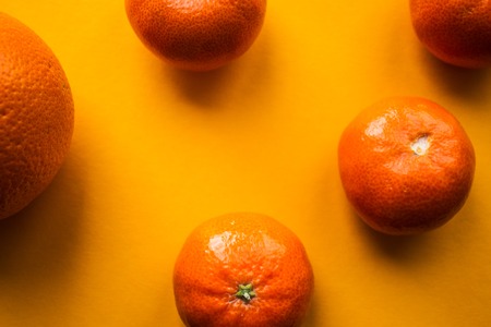 ripe mandarins and orange on a orange bacgroundの写真素材