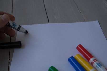 drawinga with a felt-tippers on white sheet of piper on a grey wooden bacground