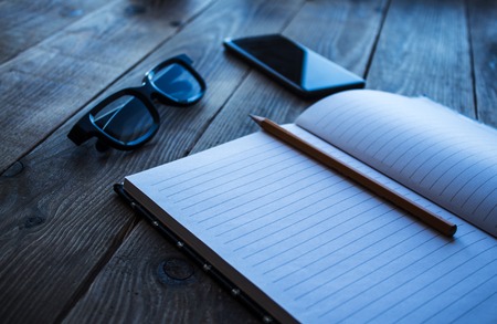 a notebook and pencil phone glasses on wooden bacgroundの写真素材