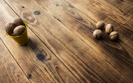 a nuts in a small bucket on a wooden backgroundの写真素材
