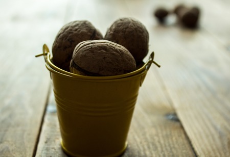 a nuts in a small yellow bucket on a wooden backgroundの写真素材