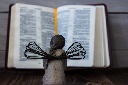 prey angel and bible on a wooden backgroundの写真素材