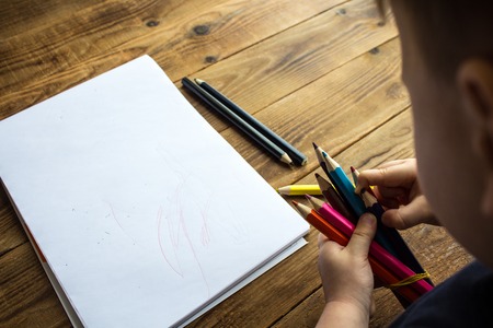 little boy holds colored pencils
