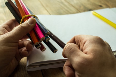 a man takes a pancil on a wooden backgroundの写真素材