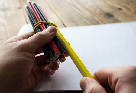 a man takes a pancil on a wooden backgroundの写真素材