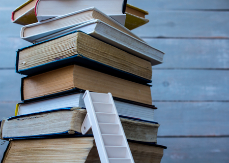 ladder on pile of old books on wooden backgroundの写真素材