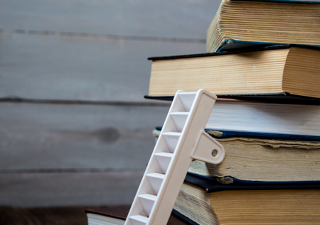 ladder on pile of old books on wooden backgroundの写真素材