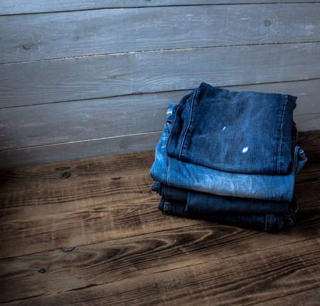 a pile of jeans on a grey wooden backgroundの写真素材