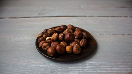 not peeled hazelnut in a bowl on a wooden backgroundの写真素材