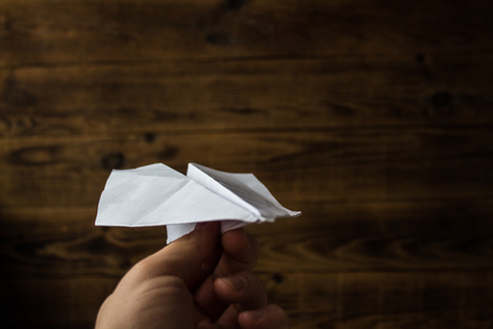 paper plane in a hand on wooden backgroundの写真素材