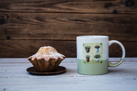 cup of coffee and a cupcake on a plate on wooden backgroundの写真素材