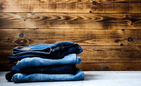 a pile of jeans on a wooden background