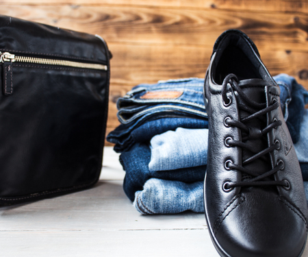 a shoes on a pile of jeans and bag on a wooden backgroundの写真素材
