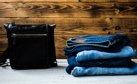 a pile of jeans and bag on a wooden backgroundの写真素材