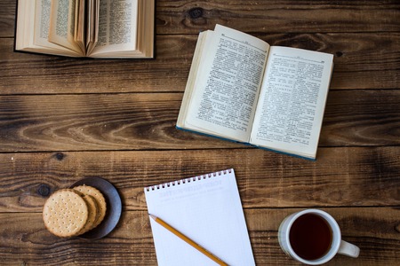 cookies and tea open book pencil notebook on wooden backgroundの写真素材