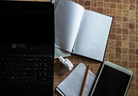 a laptop tablet and notebook with pencil on the tableの写真素材