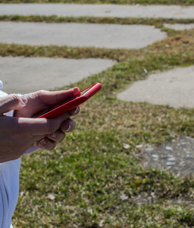 a women is holding a phone against the background of the grassの写真素材