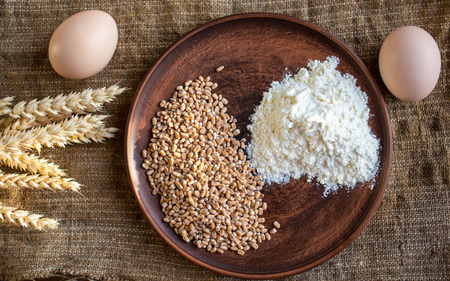 a wheat flour eggs and spikelets of wheat on sackcloth backgroundの写真素材