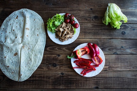 a pita grilled meat tomatoes pepper on a plate and salad on wooden backgroundの写真素材
