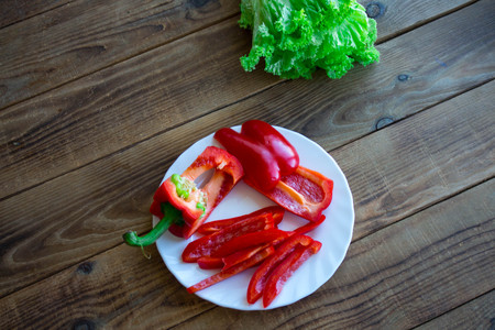 chopped pepper on a plate and salad on wooden background