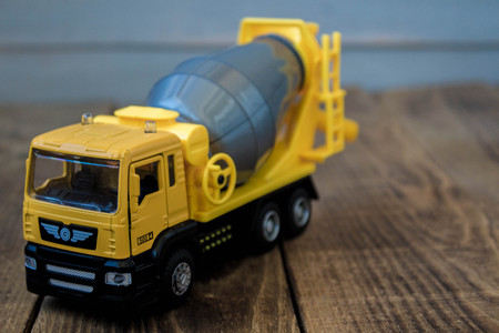 yellow toy concrete mixer on a wooden backgroundの写真素材