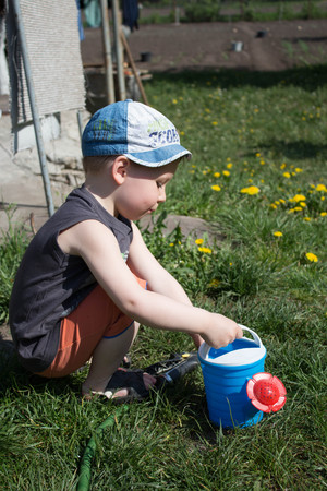 boy and watering can play outdoorの写真素材