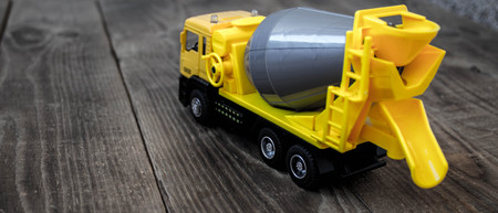 a yellow toy concrete mixer on a wooden backgroundの写真素材