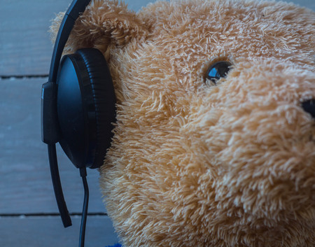 teddy bear in the headphones on wooden backgroundの写真素材