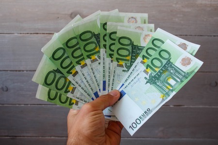 money in a hand on a wooden backgroundの写真素材
