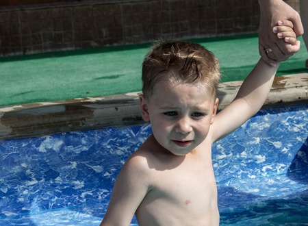 the litlle boy holds his mother hand in the poolの写真素材