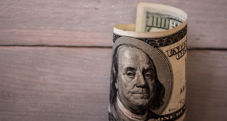 one hundred dollar bils on wooden background