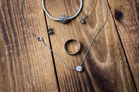 a ring and bracelet and earrings and chain with pendant on wooden backgroundの写真素材