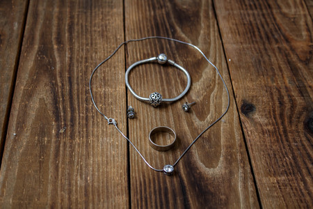 a ring and bracelet and earrings and chain with pendant on wooden backgroundの写真素材