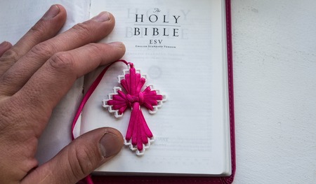 open holy bible with a cross and man hand on a white background