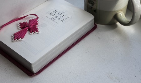 open holy bible with a cross with a cup of coffee on a white background