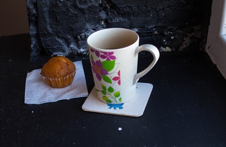 cup with tea and cupcake near the windowの写真素材
