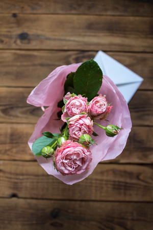 bouquet of roses in a vase with envelope on wooden backgroundの写真素材
