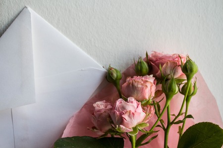 white envelope and roses on white background