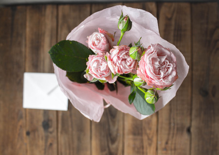 roses in a vase with envelope on wooden grey backgroundの写真素材