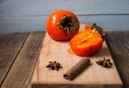 a ripe sliced persimmon on a wooden backgroundの写真素材