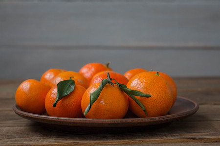 a ripe tasty tangerines on a plate on a wooden backgroundの写真素材
