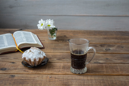 a coffee cupcake flowers and open book on a wooden backgroundの写真素材