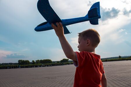 a boy playing with a airplane in the streetの写真素材