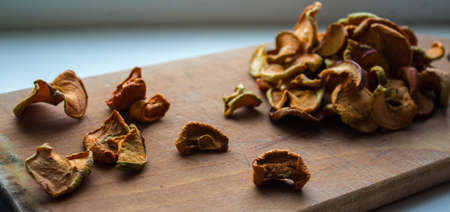 a dried apples slices on a wooden plate on a white backgroundの写真素材
