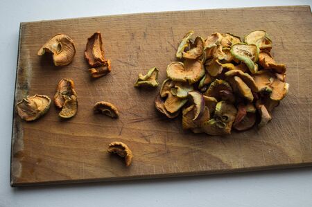dried apples on a wooden plate on a white backgroundの写真素材