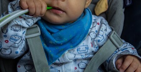 the baby holds a spoon in his hands in the kitchenの写真素材
