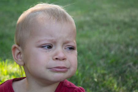 a crying baby in the backyard with tearsの写真素材