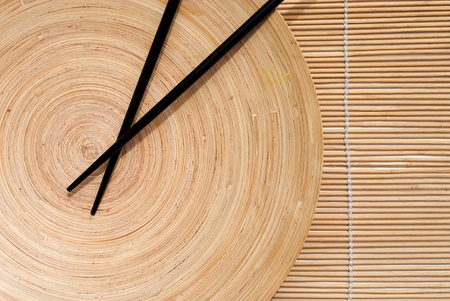 japanese chopsticks in wooden round dish on bamboo placemat background の写真素材